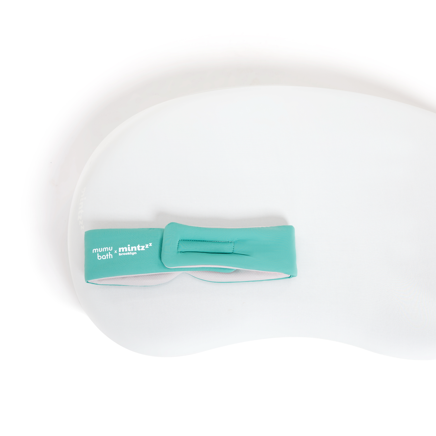 A white, contoured foam bath pillow with a teal Mintzzz strap on the upper left is perfect for relaxing after wearing your Chill Mask | Cooling Sleep Mask.