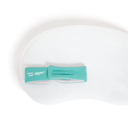 A white, contoured foam bath pillow with a teal Mintzzz strap on the upper left is perfect for relaxing after wearing your Chill Mask | Cooling Sleep Mask.