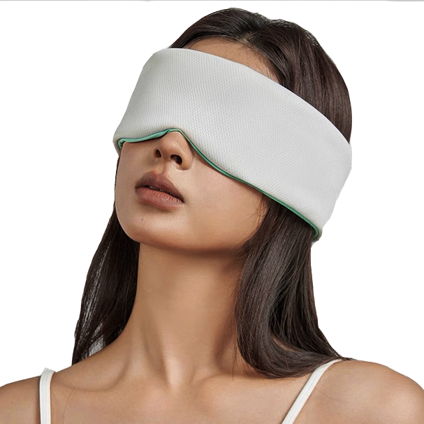 A woman with long dark hair wears a white sleeveless top and the Mintzzz Chill Mask | Cooling Sleep Mask, a large, breathable sleep mask that covers her eyes and upper face.