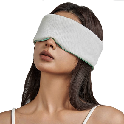 A woman with long dark hair wears a white sleeveless top and the Mintzzz Chill Mask | Cooling Sleep Mask, a large, breathable sleep mask that covers her eyes and upper face.